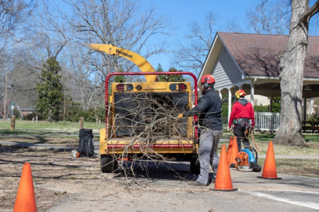 Heartland Tree Service crew loading tree branches into a wood chipper after completing a residential tree service project in Hazelwood, MO.